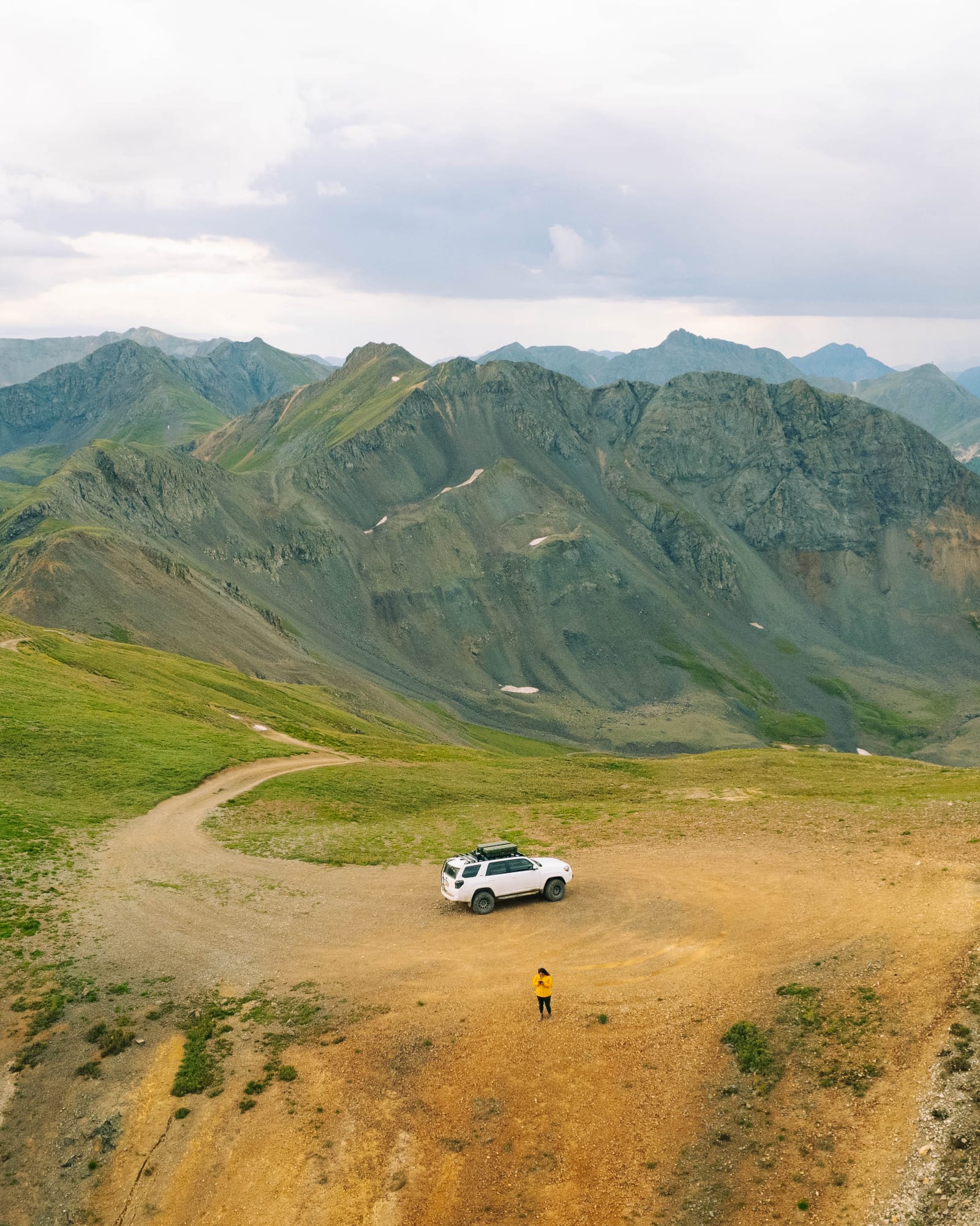 Overland rig at a high alpine pass with green ridgelines behind