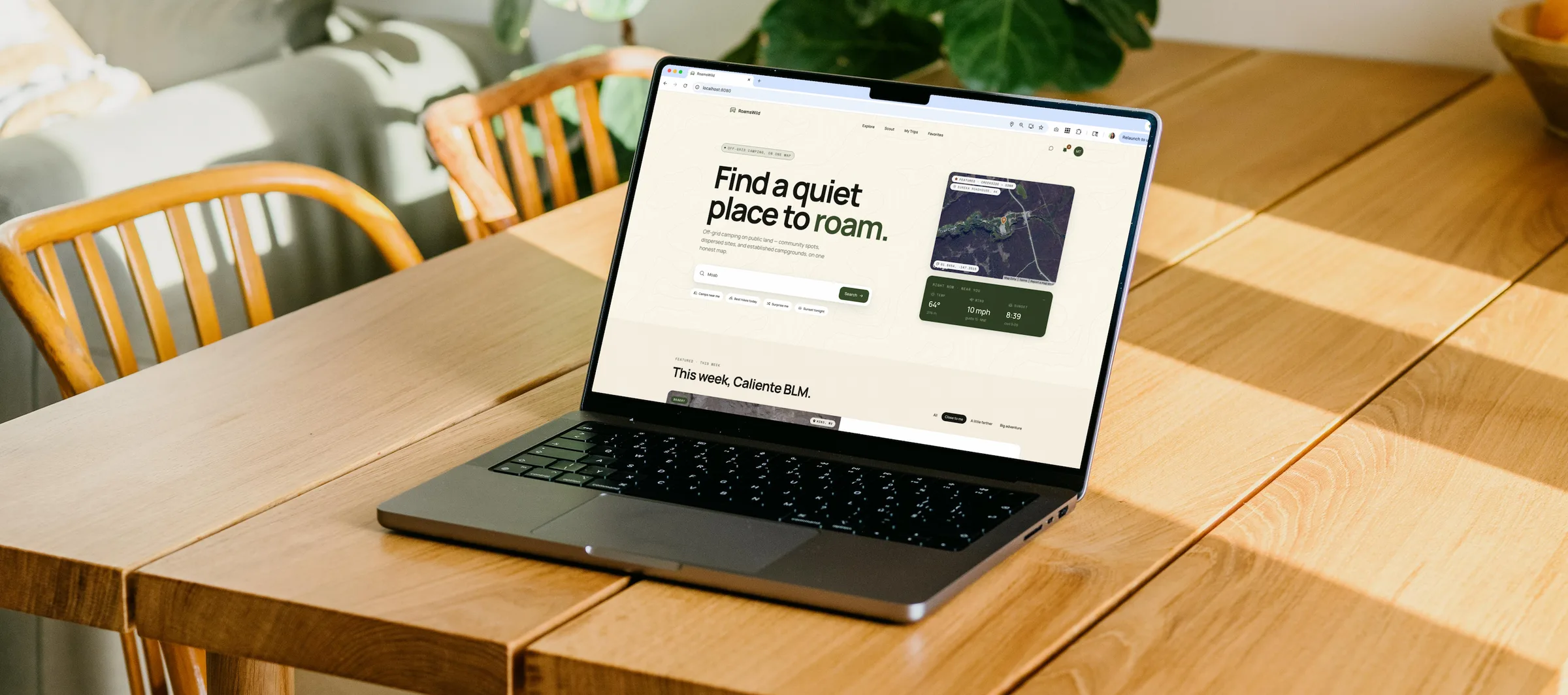 RoamsWild 'Find a quiet place to roam' landing page on a MacBook on a sunlit wood table